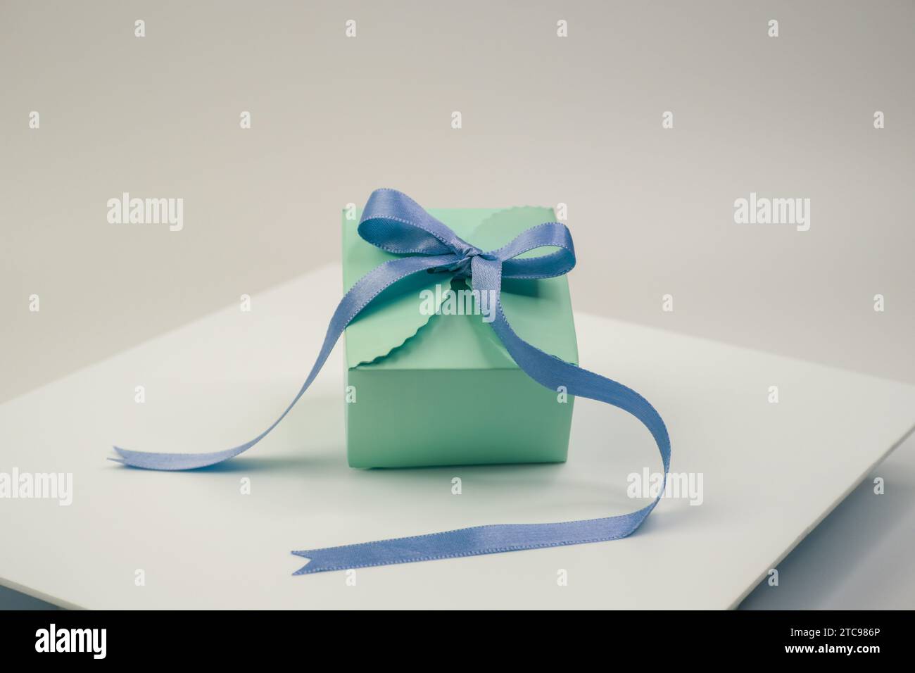 An isolated image of a colorful present, wrapped in blue and green paper, sitting on a white plate Stock Photo