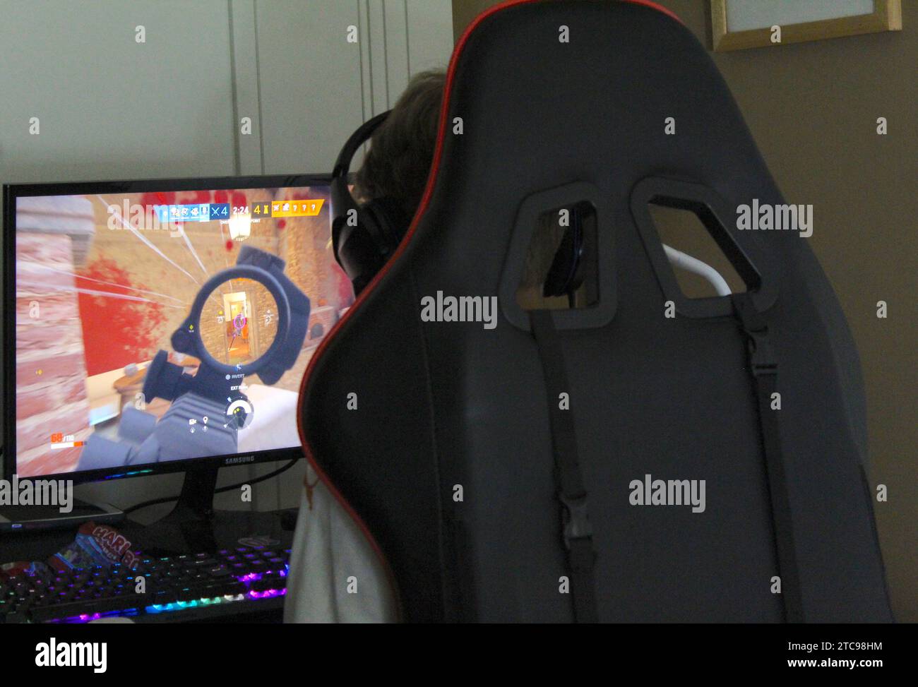 An over the shoulder shot of a young boy gaming in his gaming chair with his pc computer. Stock Photo