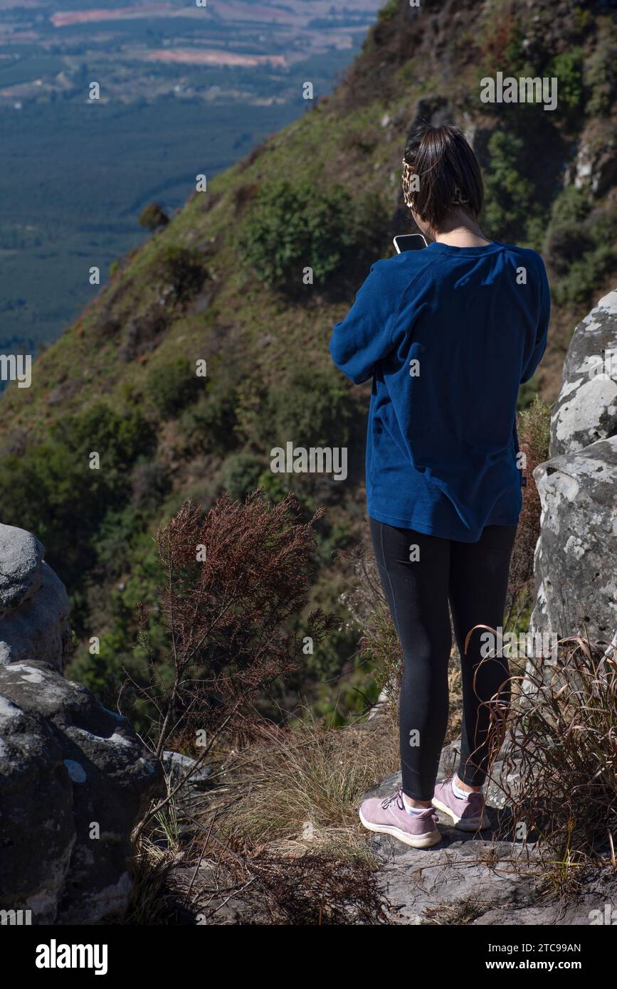 Young lady dressed in casual sportswear out hiking taking a picture with her cell phone Stock Photo