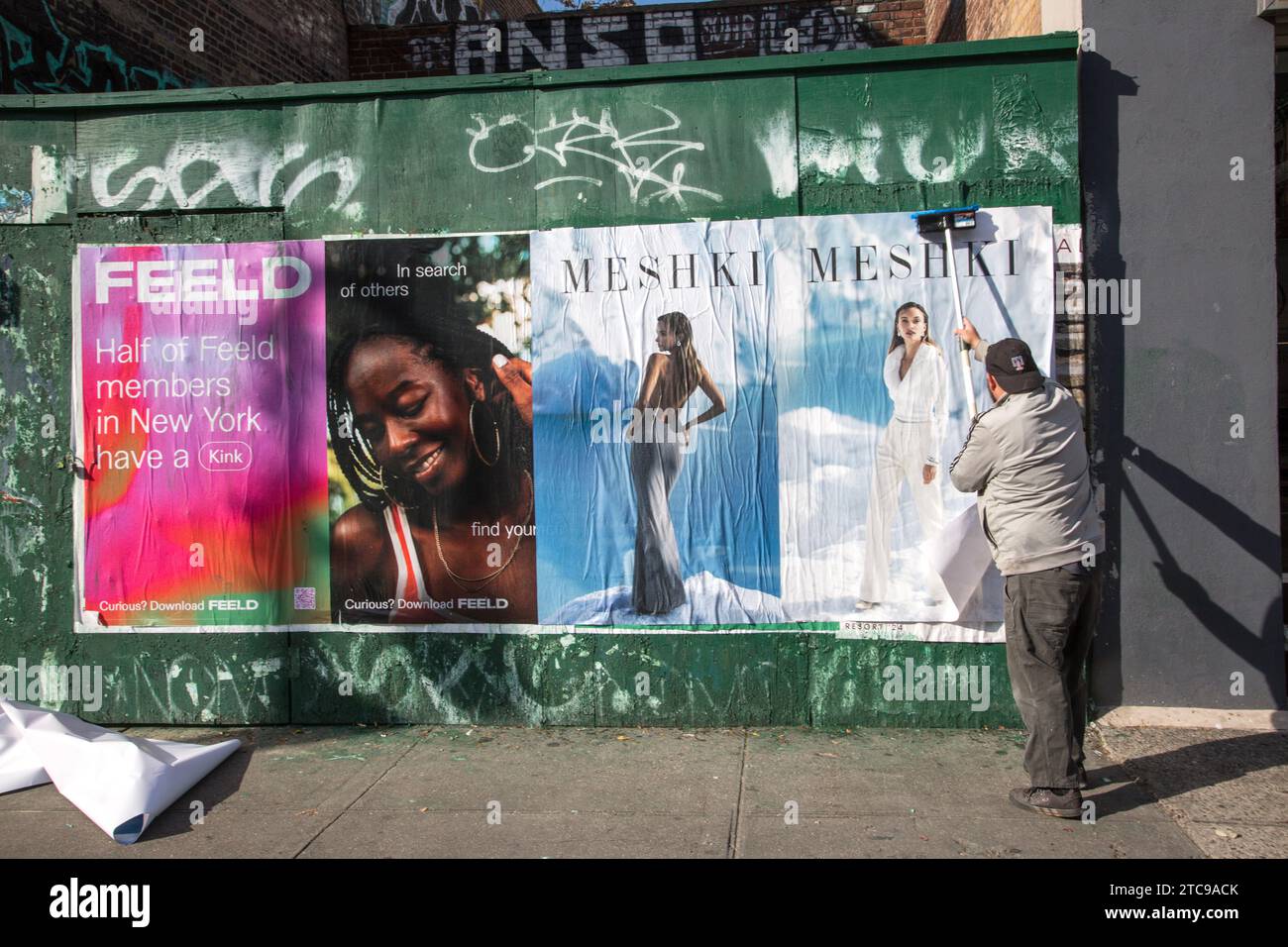 Worker putting up advertising posters along the sidewalk on 6th Avenue in Greenwich Village, New York City. Stock Photo