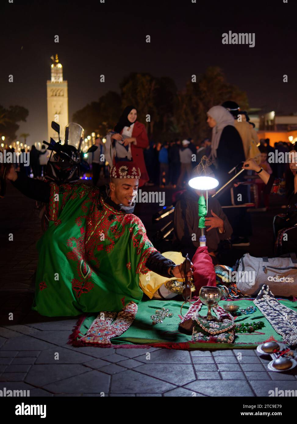 Young man in traditional costume with trinkets at Jemaa el-Fna Square at night in the city of Marrakesh aka Marrakech, Morocco, December 11, 2023 Stock Photo