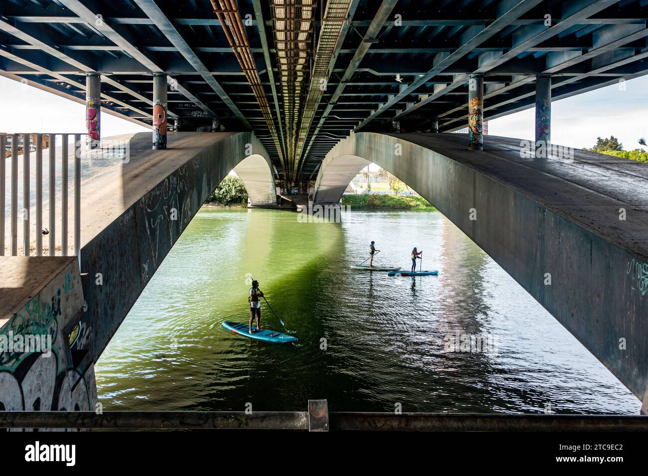 Paddle boarders under a bridge on the Guadalquivir River in Seville, Spain Stock Photo