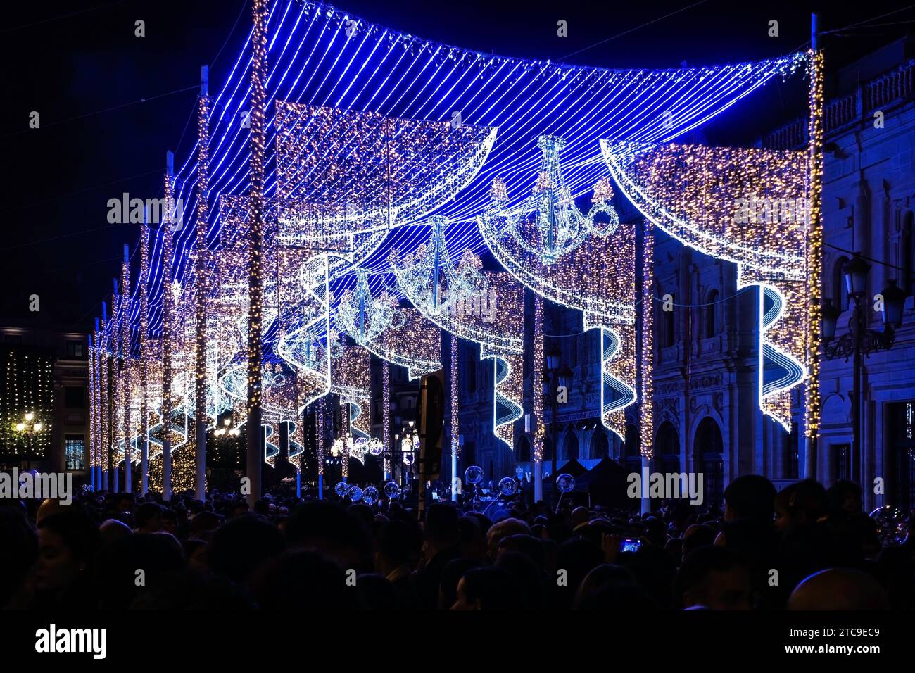A sea of spectators under a canopy of blue holiday lights, creating a festive urban nightscape. in Seville, spain. Stock Photo