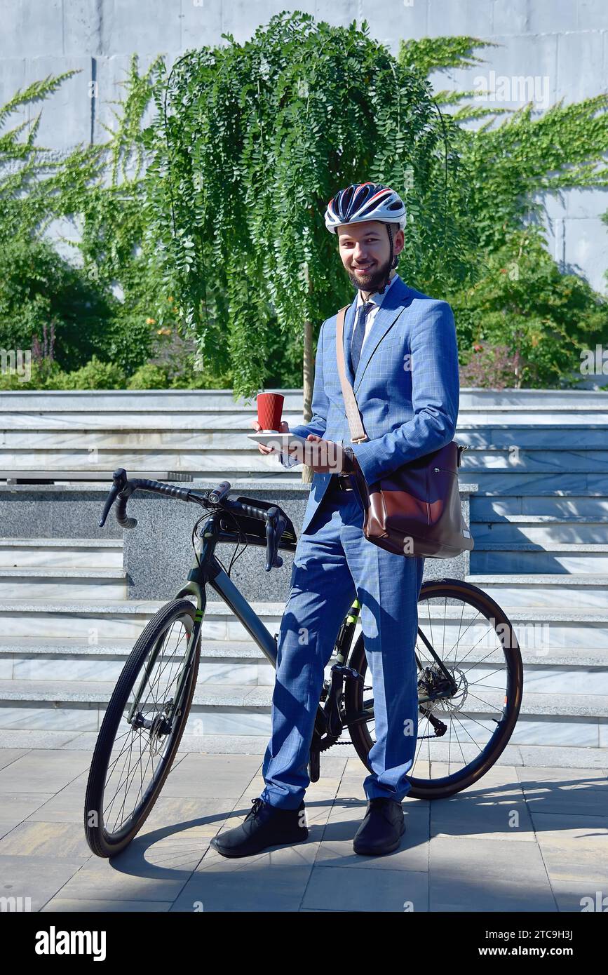 Businessman in helmet with bike using digital tablet computer. Business and alternative transport concept. Stock Photo