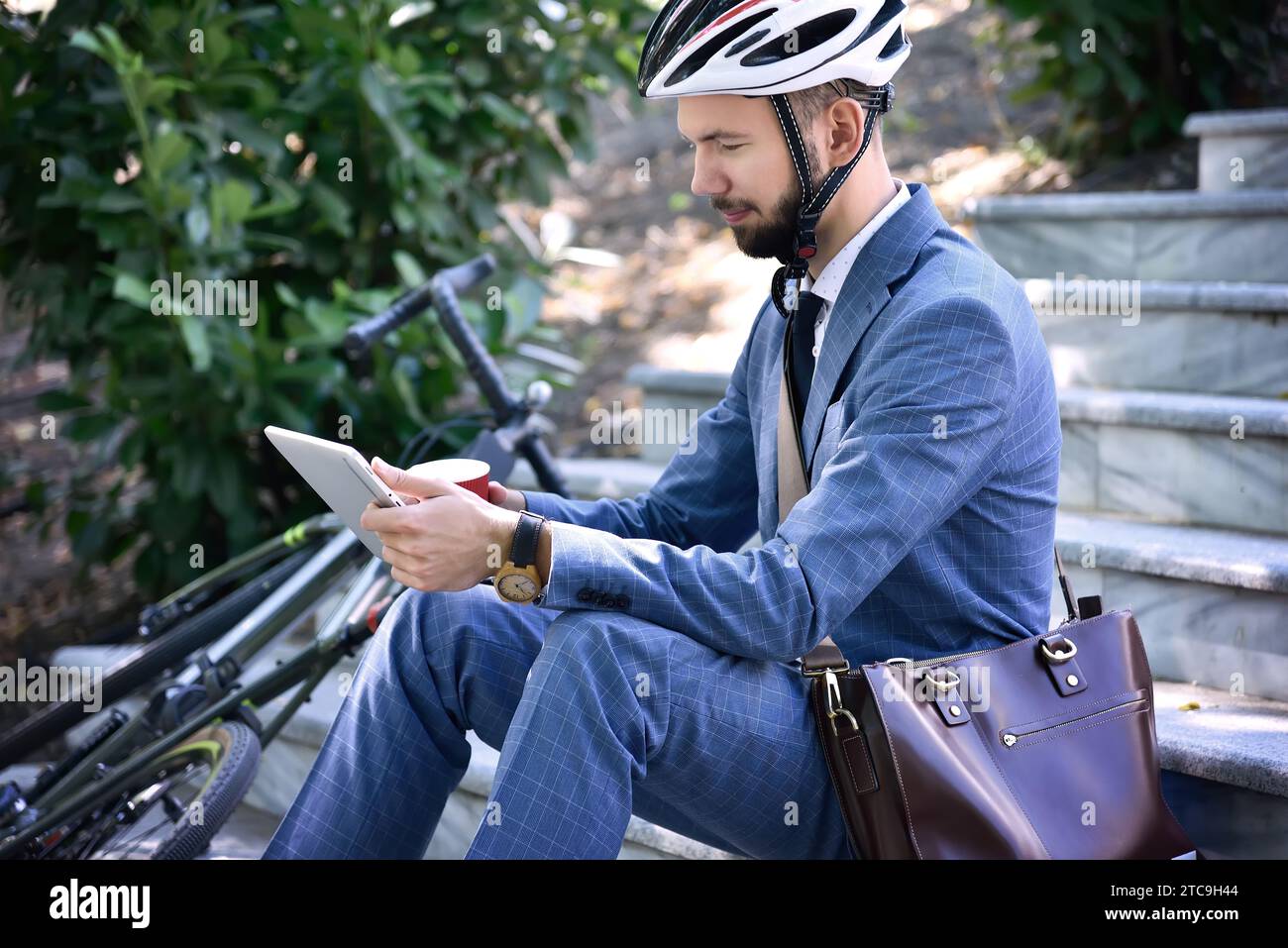 Young businessman sitting on stairs and using digital tablet computer. Business and working concept. Stock Photo