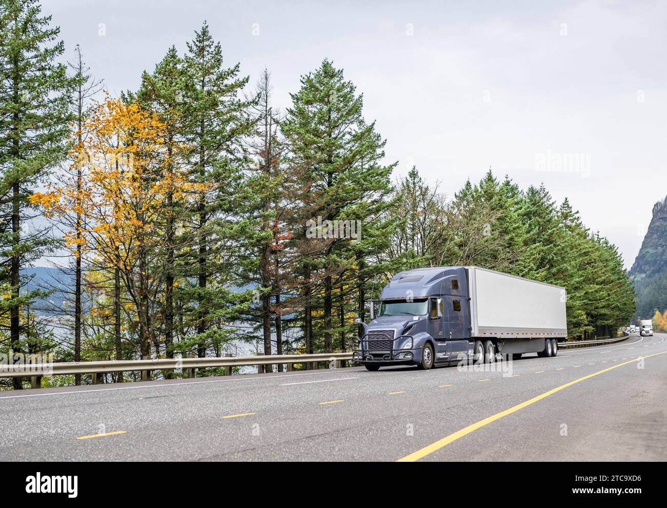 Classic carrier big rig gray semi truck with extended cab for truck driver rest transporting cargo in dry van semi trailer driving on highway road wit Stock Photo