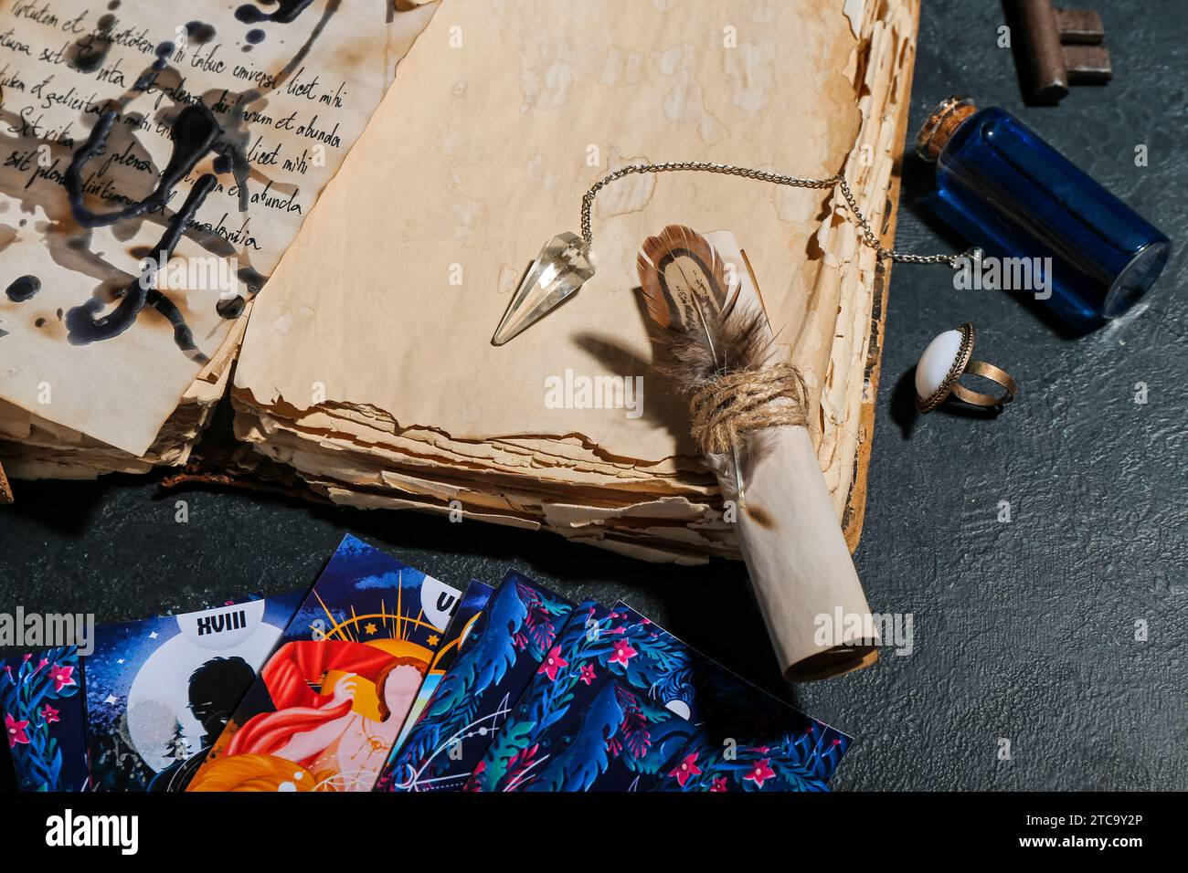 Witch's magic attributes with book and tarot cards on dark table, closeup Stock Photo