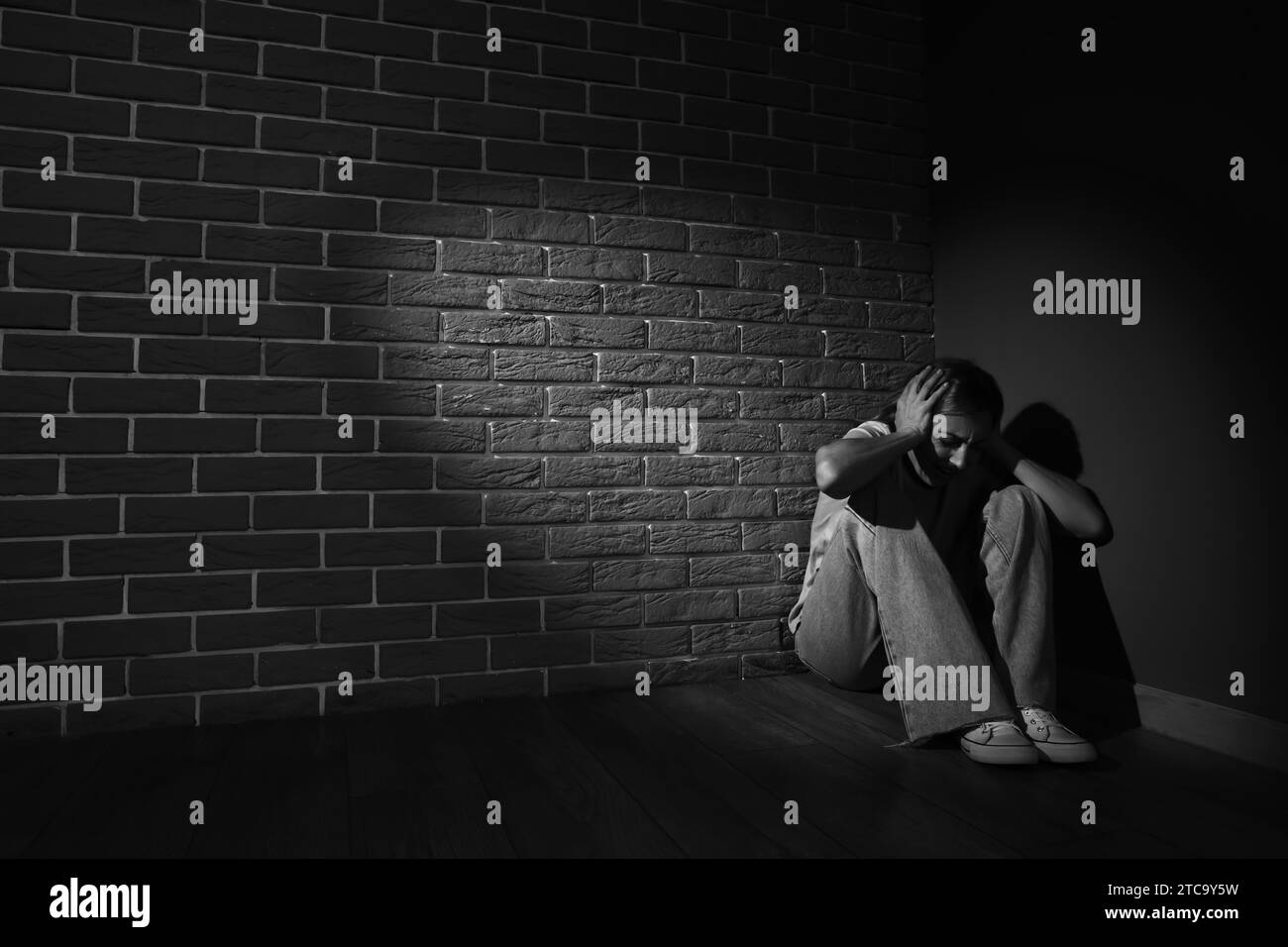 Scared mature woman sitting in corner Stock Photo - Alamy