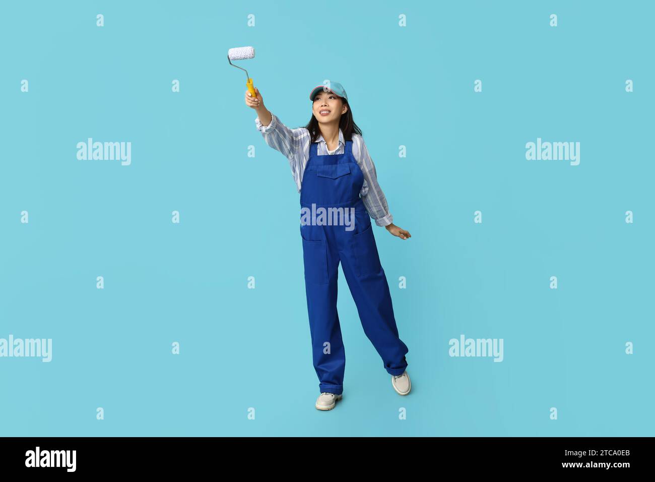 Female Asian painter with roller on blue background Stock Photo - Alamy