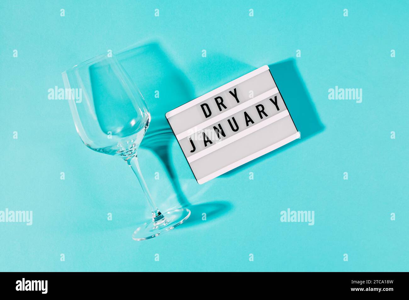 Text Dry January on the decorative lightbox and empty wine glass isolated on blue background, top view Stock Photo