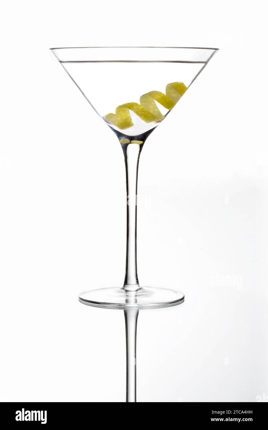 Martini mixed drink with olive garnish on a light grey background with