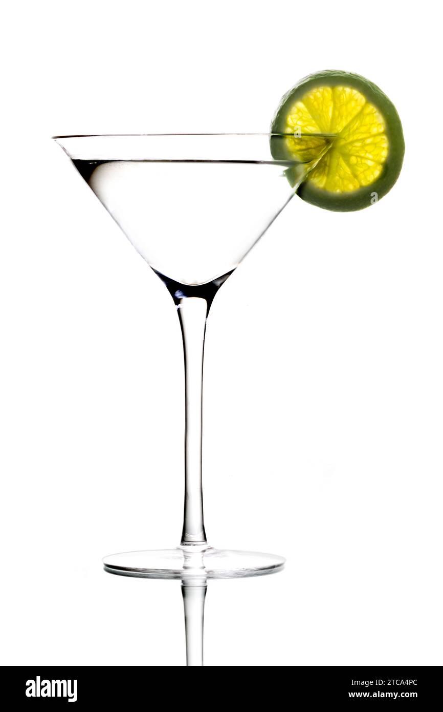 Martini mixed drink with lime garnish on a light grey background with reflection Stock Photo