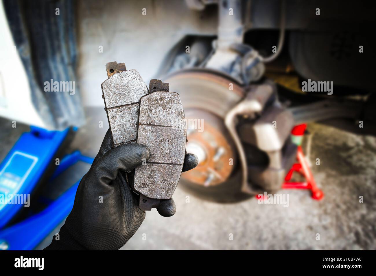 Used car brake pads in the hands of a mechanic with brake discs and
