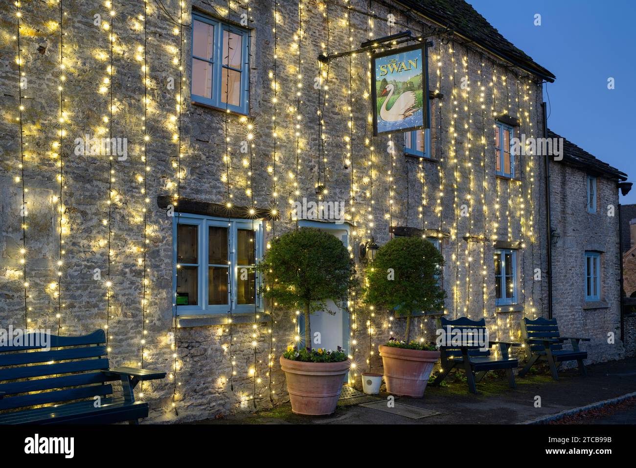 Christmas lights on The Swan pub at dusk. Southrop. Cotswolds, Gloucestershire, England Stock Photo