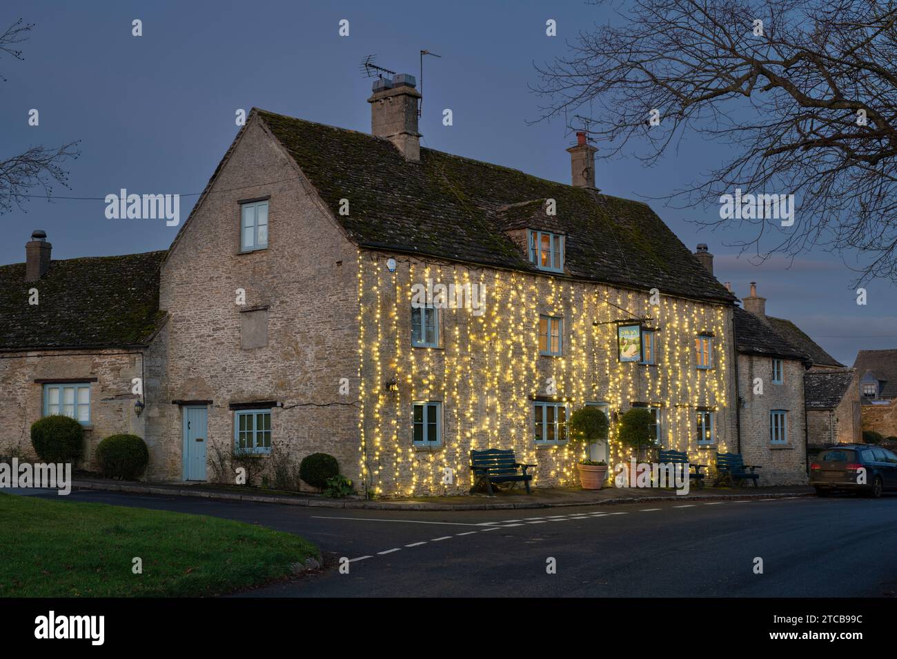 Christmas lights on The Swan pub at dusk. Southrop. Cotswolds, Gloucestershire, England Stock