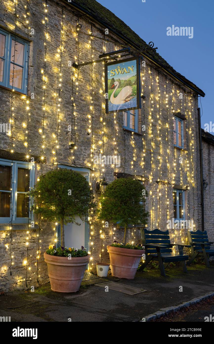 Christmas lights on The Swan pub at dusk. Southrop. Cotswolds, Gloucestershire, England Stock
