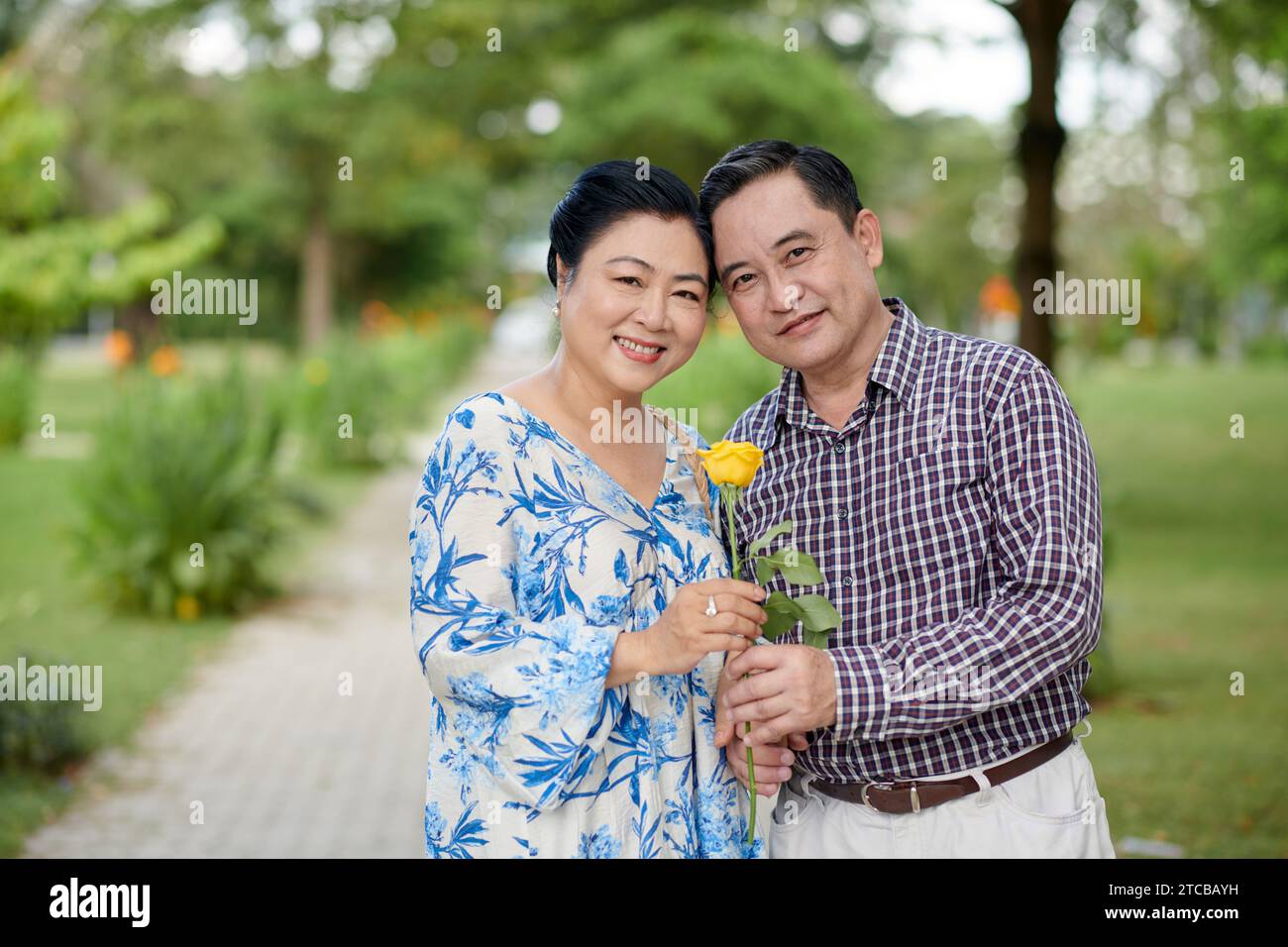 Portrait Of Happy Senior Vietnamese Couple Hugging And Holding Rose Flower When Standing On Path 1184