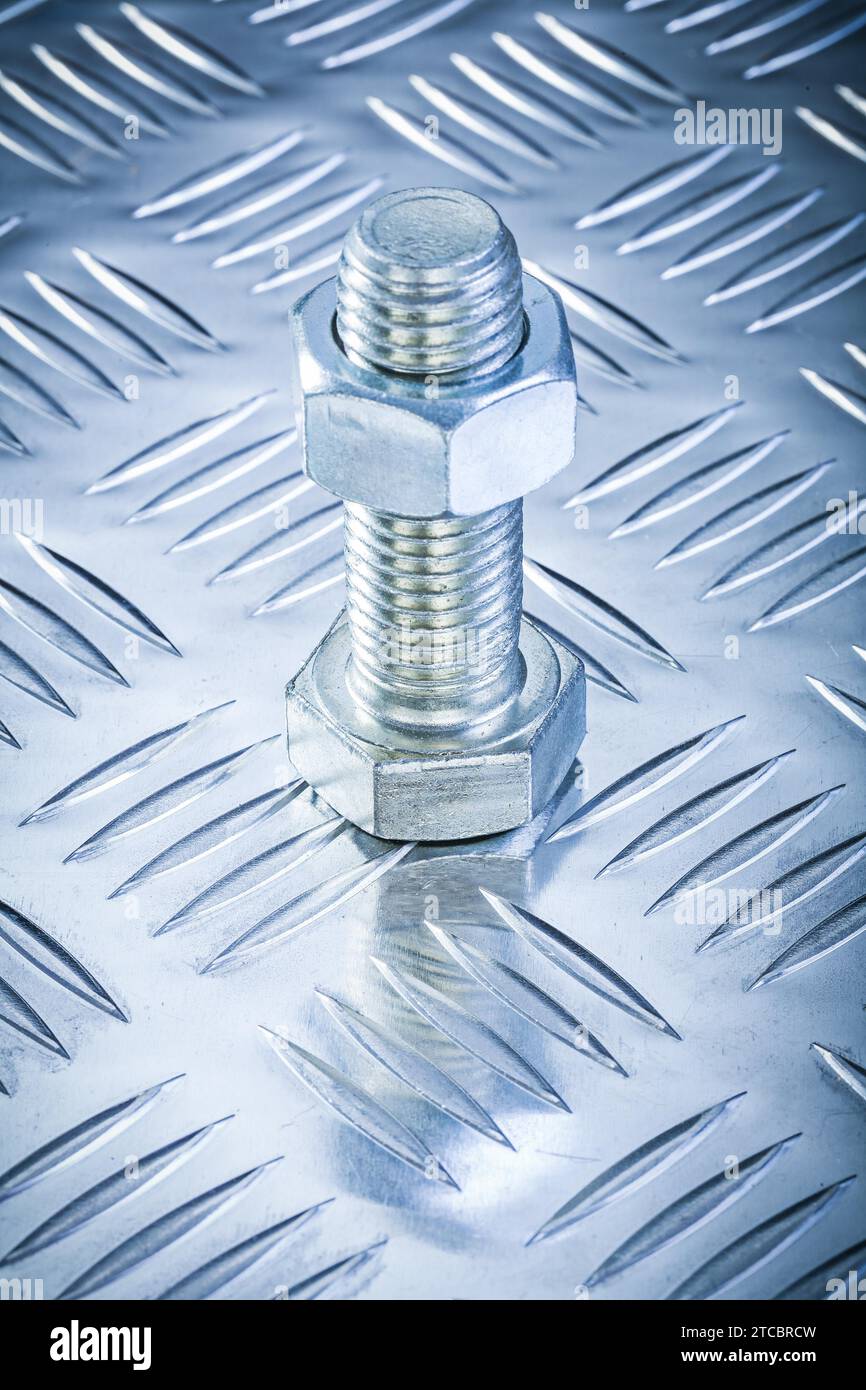 Detail of a stainless steel bolt with threaded nut on a chequer plate