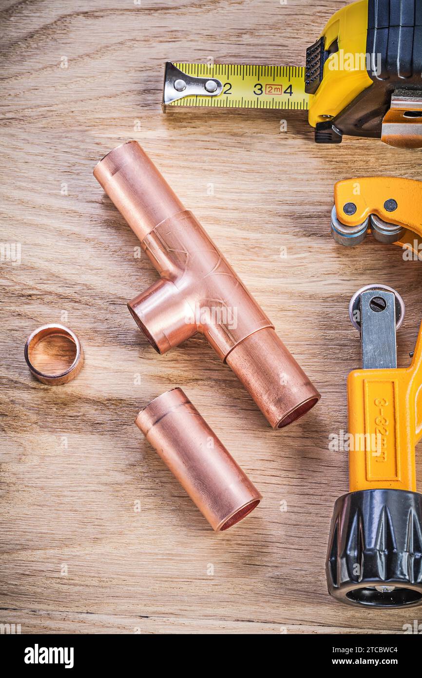 copper water pipe cutter fittings tape measure on wooden board vertical