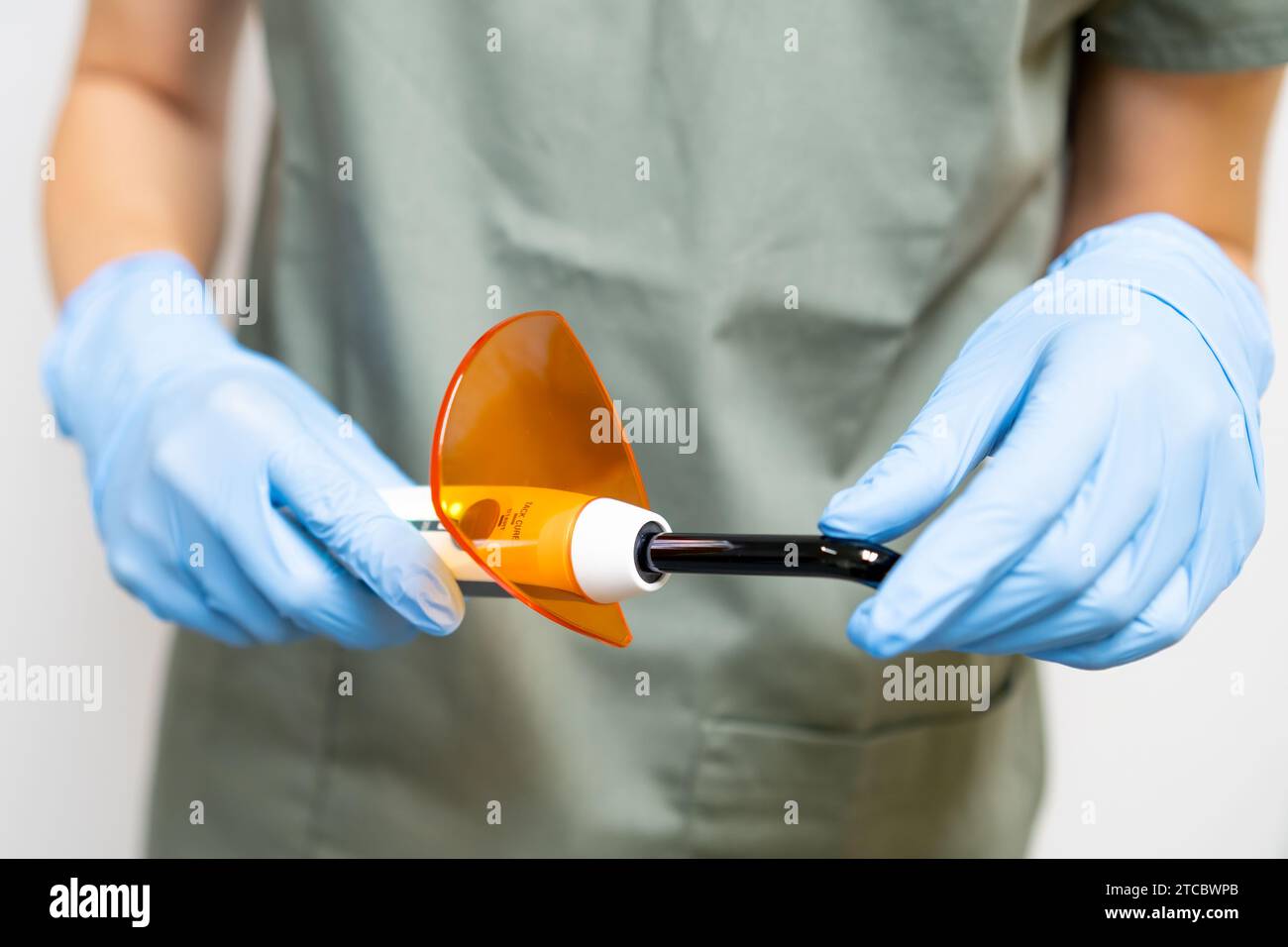 Dental ultraviolet curing light tool with orange UV light blocking glass in dentist hands Stock