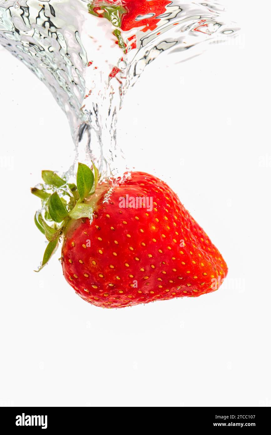 Strawberry sinking underwater with air bubbles isolated on white