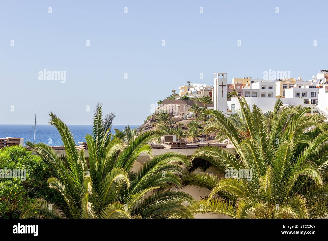 Scenic view at Morro Jable on canary island Fuerteventura, Spain with palm trees and white buildings in the foreground and the atlantic ocean in the Stock Photo