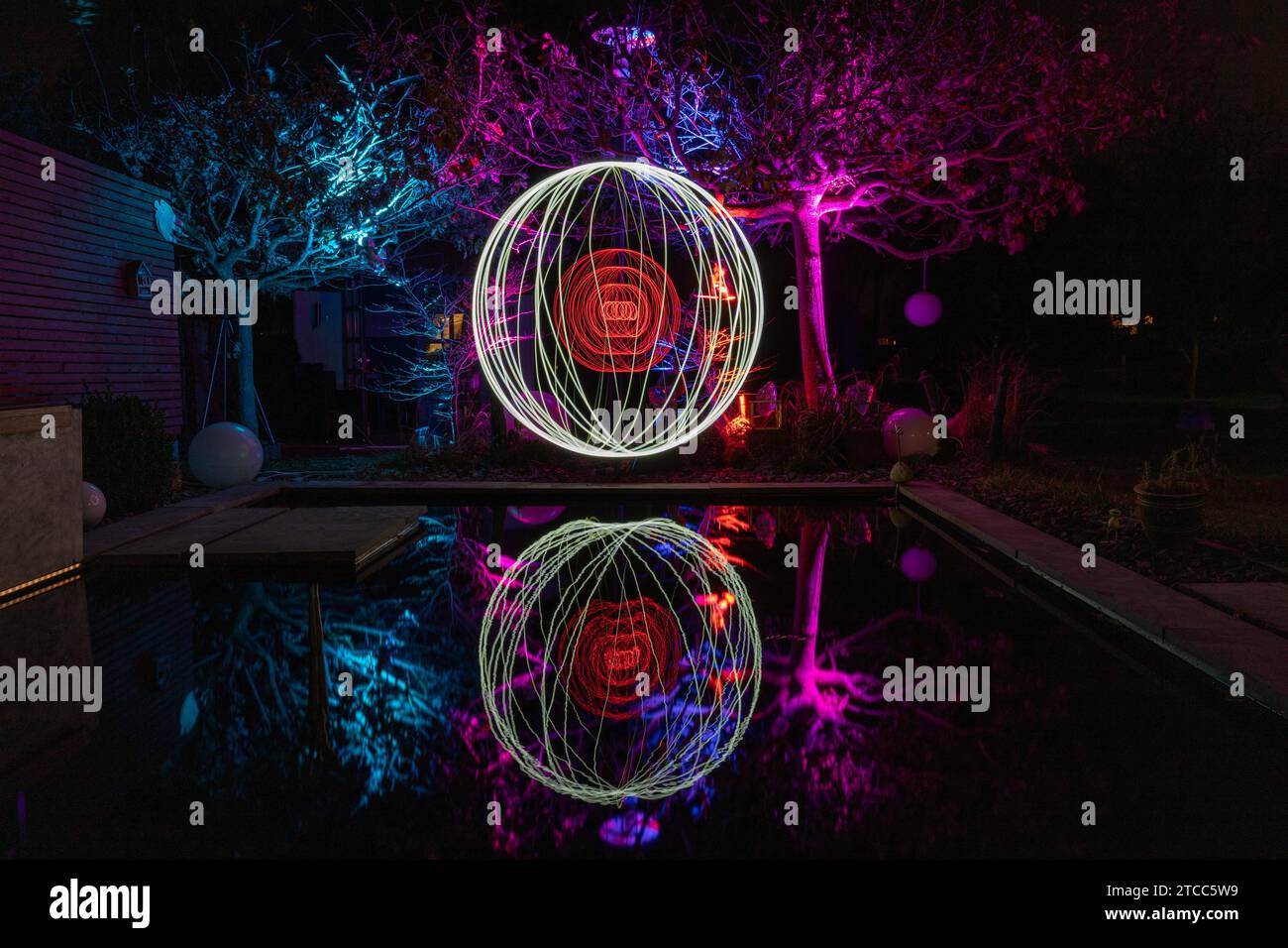 Light painting with colorfully illuminated trees and reflections in water Stock Photo