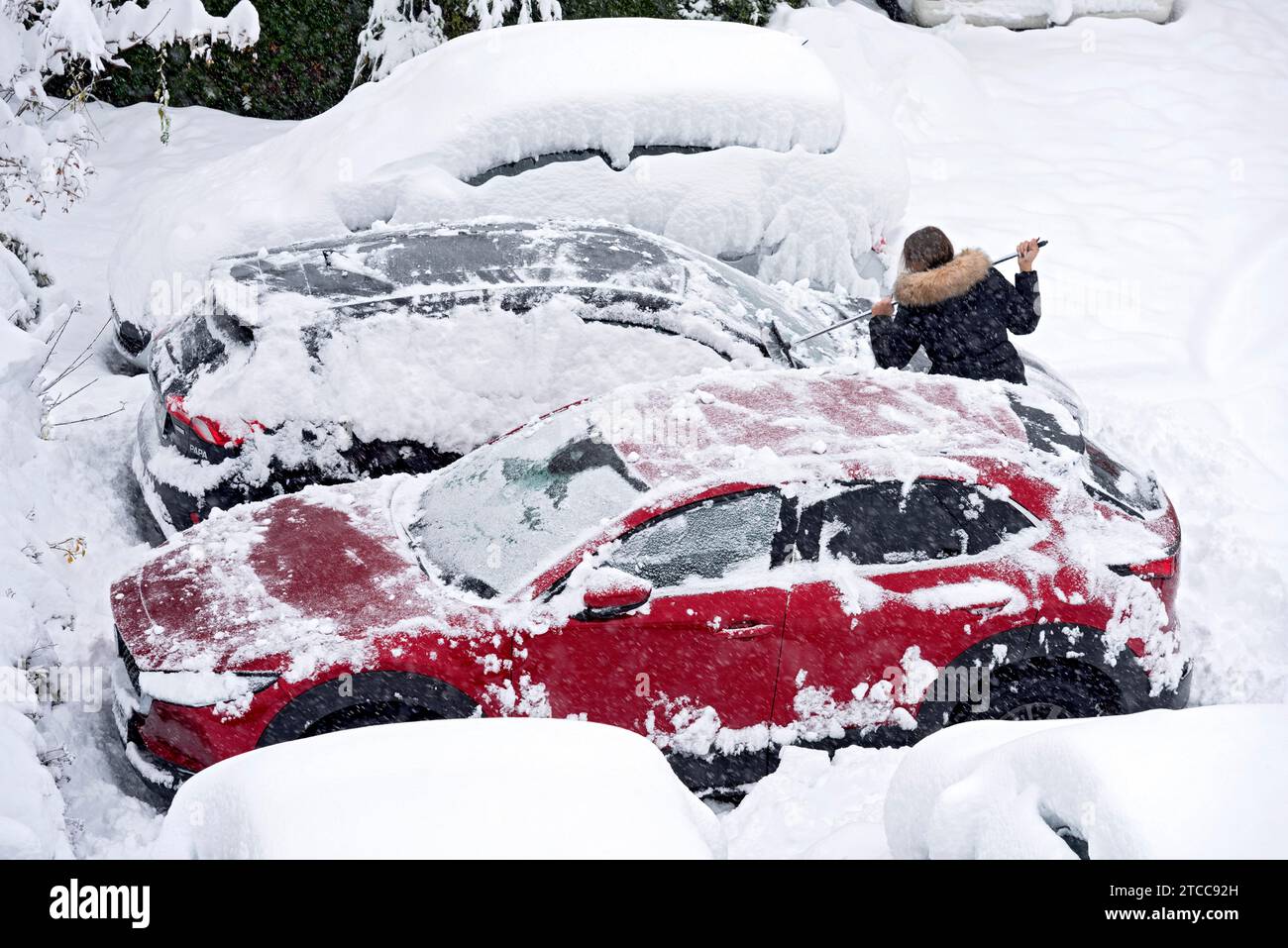 Woman removes fresh snow from car with broom, car, snowed in, heavy snowfall, snow masses, snow chaos, onset of winter, Marzling, Freising, Upper Stock Photo