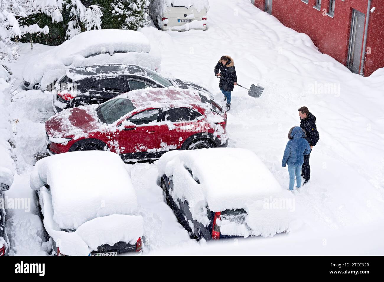 Woman shovelling snow on car park, car, car, snowed in, fresh snow, heavy snowfall, snow masses, snow chaos, snow shovel, onset of winter, Marzling Stock Photo