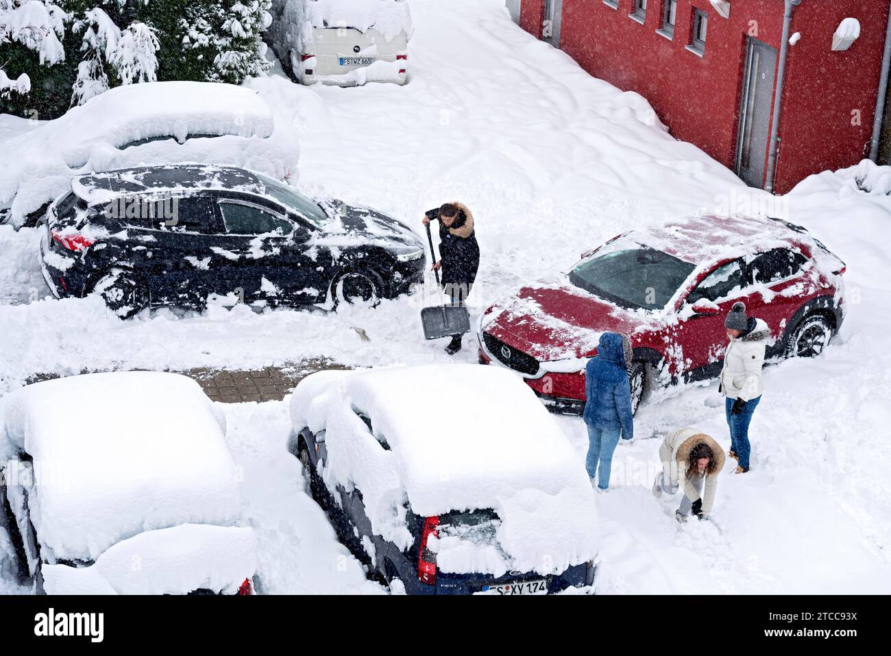 Women shovelling snow on car park, car, car, snowed in, fresh snow, heavy snowfall, snow masses, snow chaos, snow shovel, onset of winter, Marzling Stock Photo