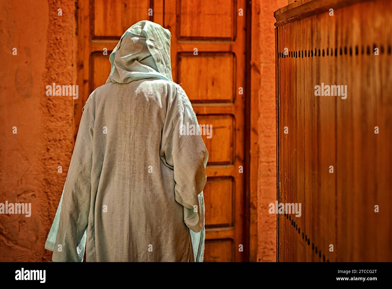 Moroccan woman wearing niqab is walking inside a Marrakech or Marrakesh Medina alley. Traditional Islamic female dress. Stock Photo