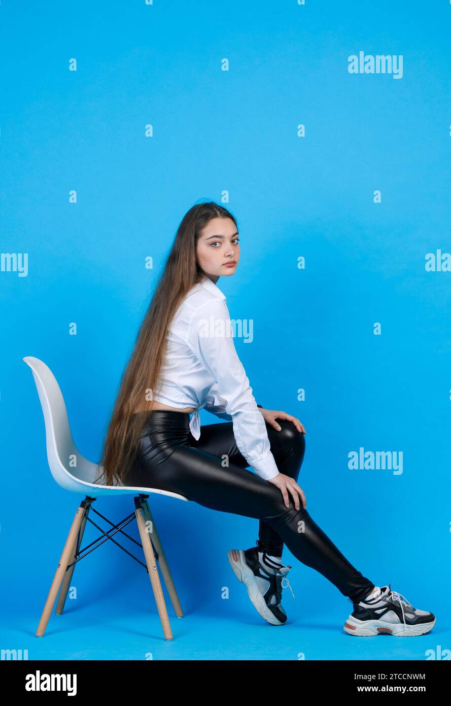 Pensive young female model with very long fair hair, leaning on knees