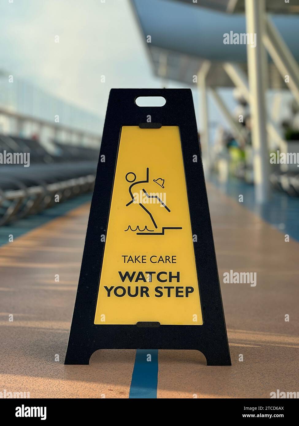 A vibrant yellow and black warning sign with the phrase Caution - WATCH YOUR STEP printed in bold black text against a bright yellow backdrop Stock Photo