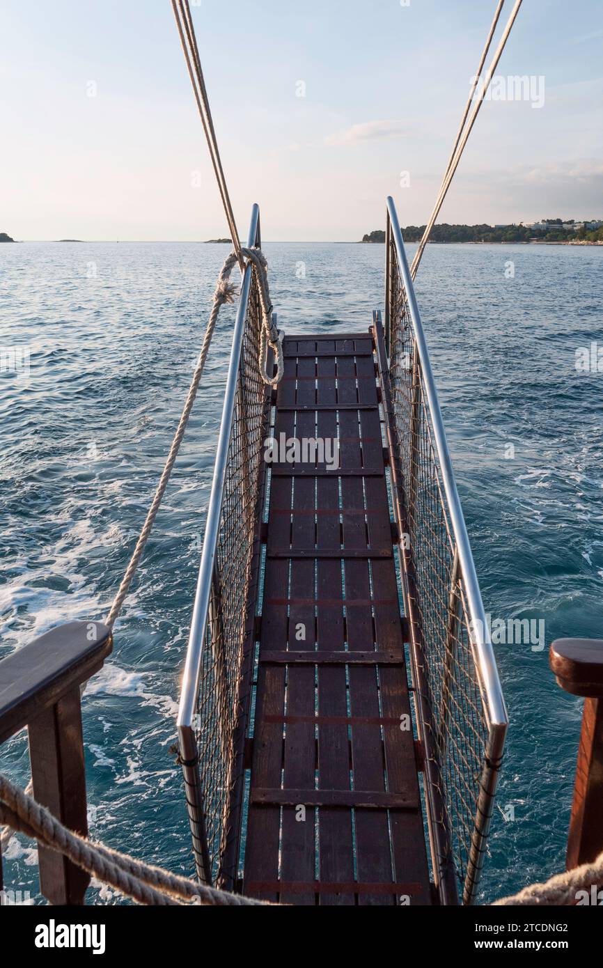 a brown wooden gangway with railing while sailing on the ocean Stock Photo