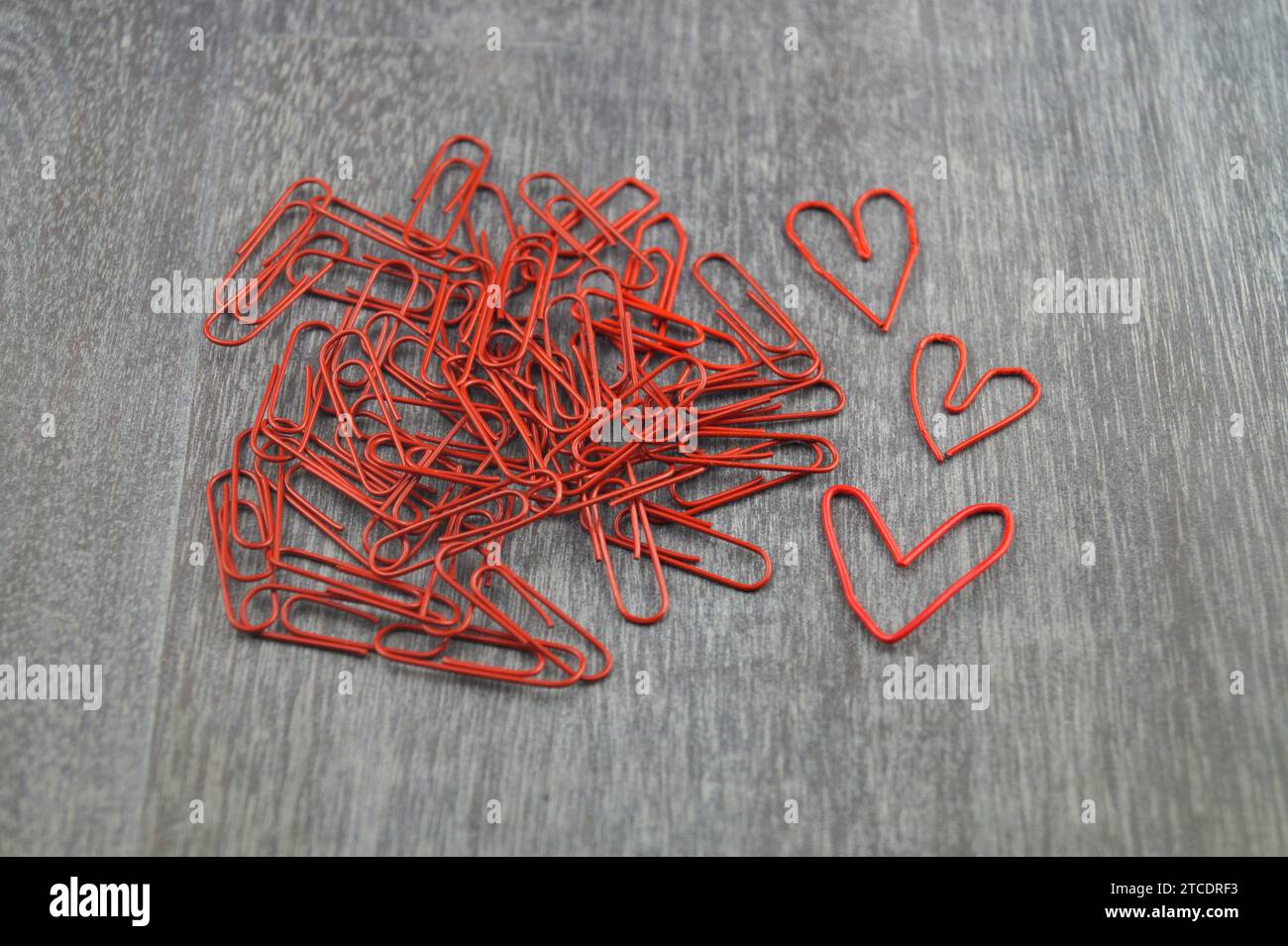 red paper-clips, three of them heart-shaped, love in the office Stock Photo