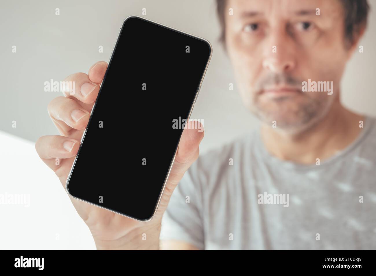 Man holding mobile phone with blank black screen as mockup copy space, selective focus Stock Photo