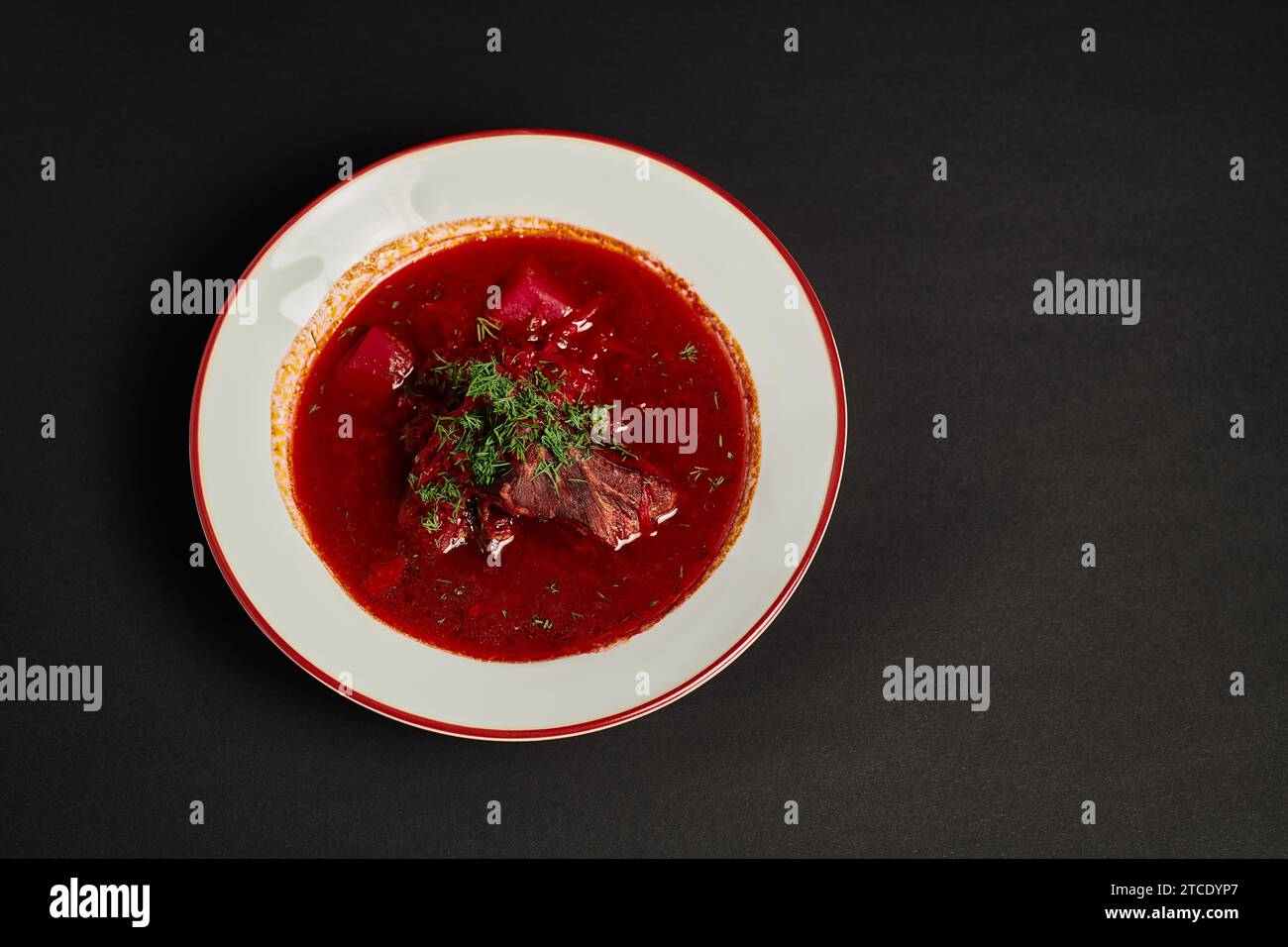 eastern European meal, traditional Ukrainian borsch with beef in ceramic bowl on black backdrop Stock Photo