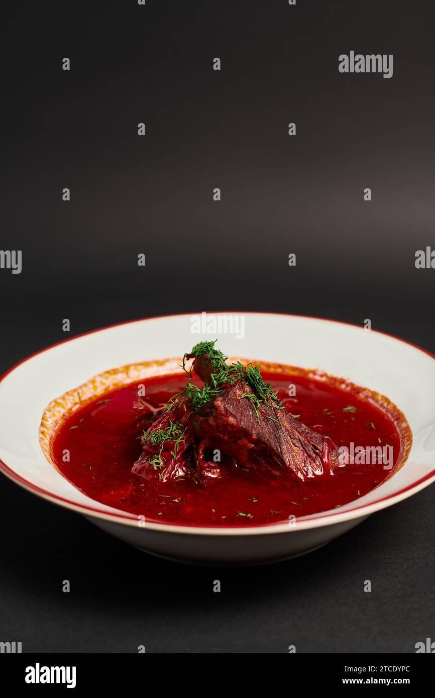 homemade meal, traditional Ukrainian borsch with beef in ceramic bowl on black backdrop Stock Photo