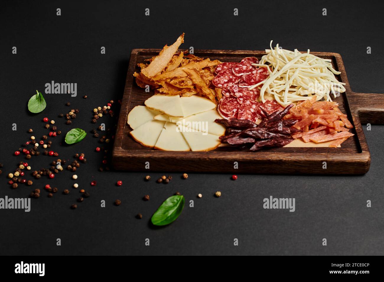 top view of charcuterie board with cheese selection, dried beef and salami on black, antipasto Stock Photo