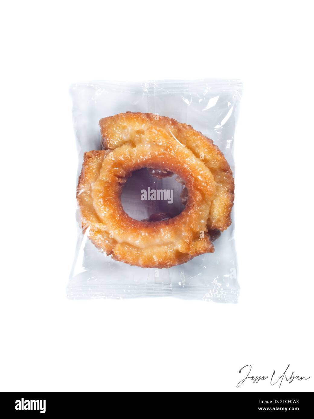 A close-up of a freshly-baked doughnut placed inside a bag on a white background Stock Photo