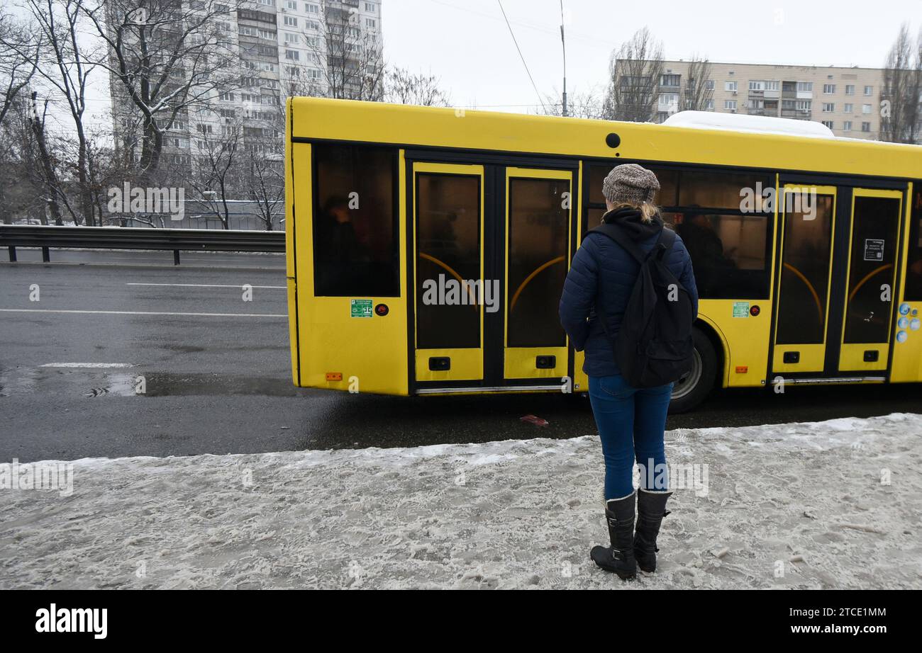KYIV, UKRAINE - DECEMBER 11, 2023 - A woman stands in front of a bus that runs between the closed metro stations of the Blue Line, Kyiv, capital of Uk Stock Photo