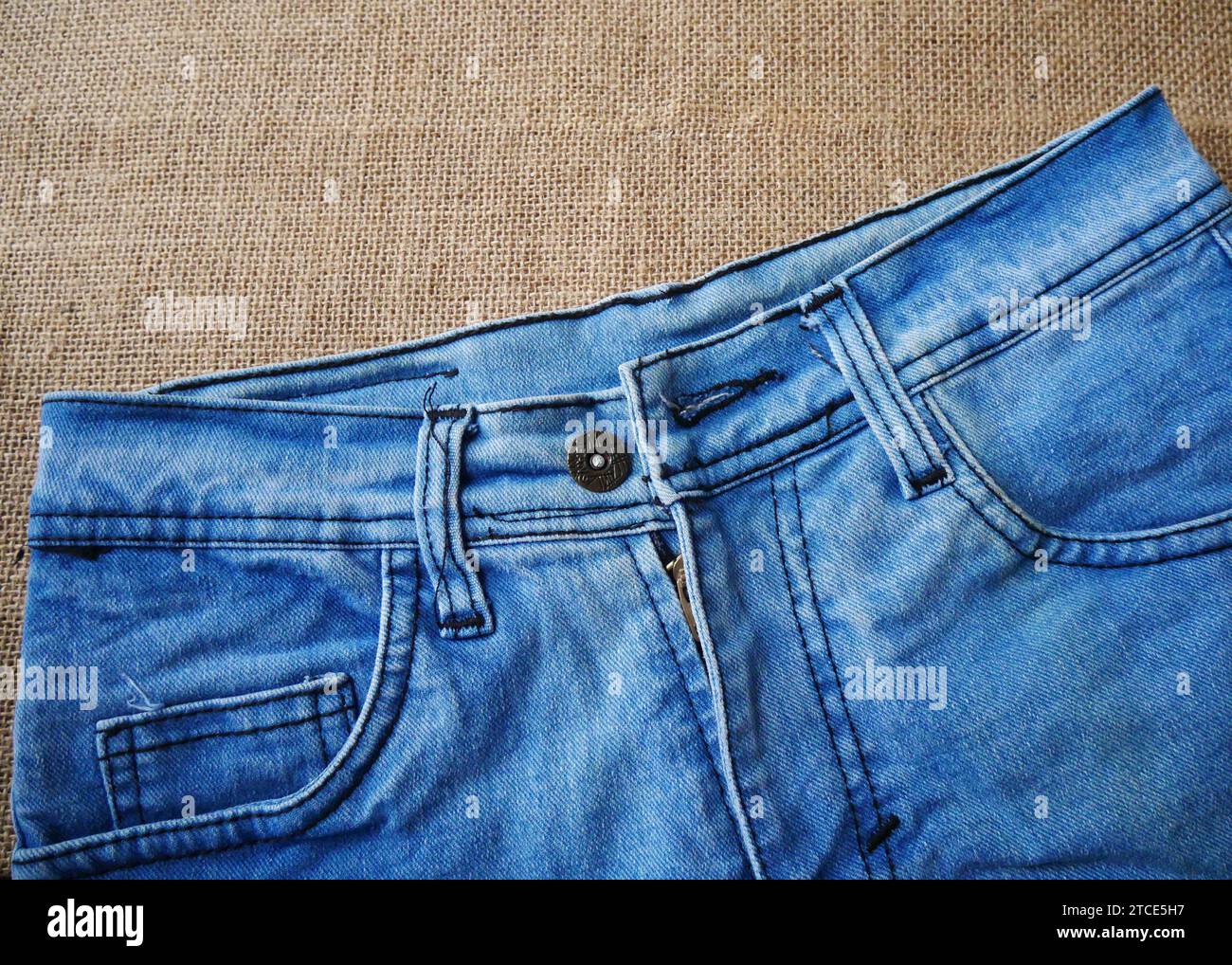 Blue jeans back view on burlap background. Jeans texture. Fashion denim background for sewing, copy space. Stock Photo