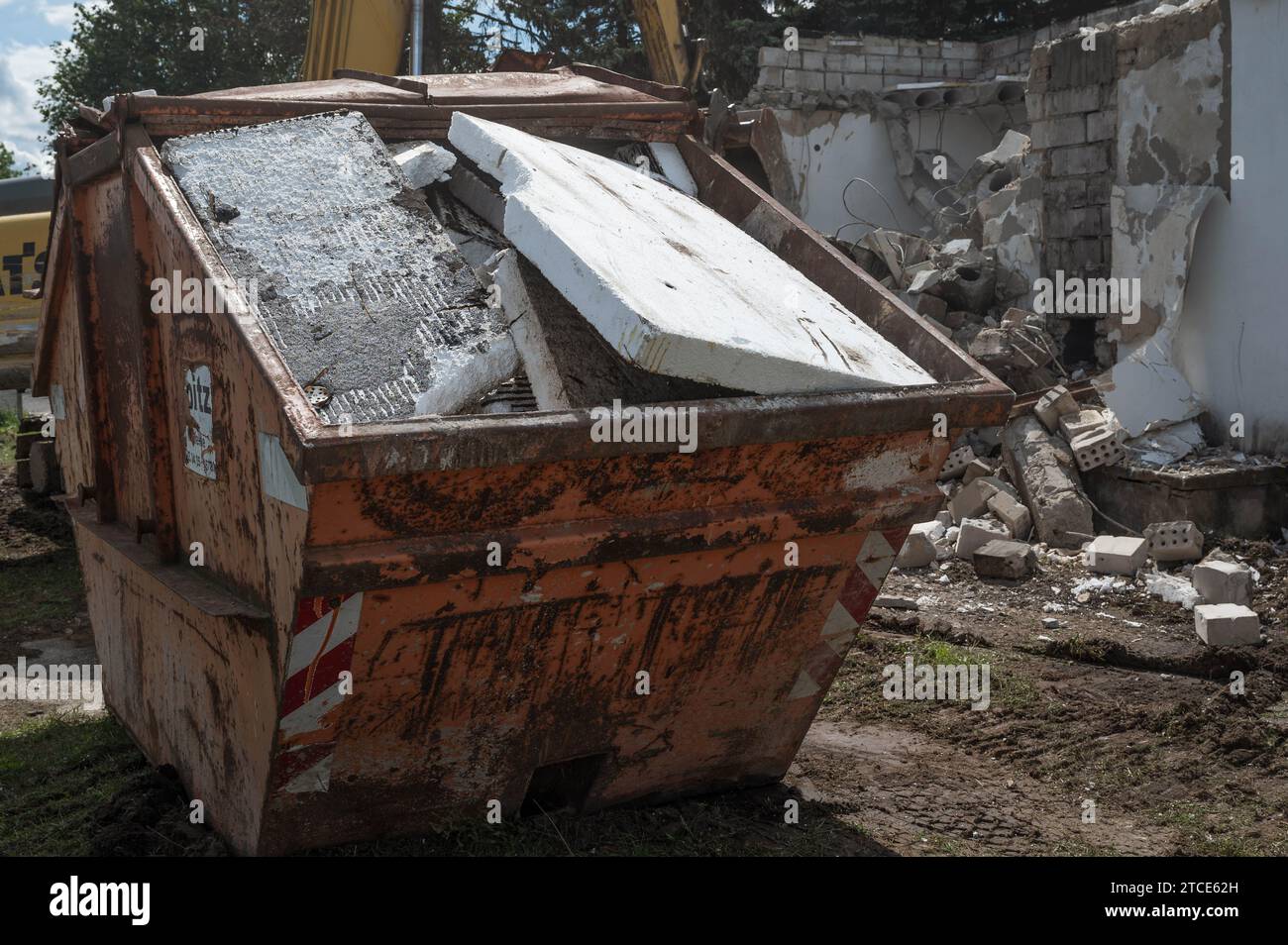 Styrofoam placed in a construction waste container, demolition of a building in the background