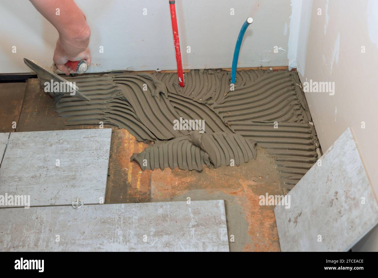 In preparation for laying floor tiles, trowel adhesive onto concrete