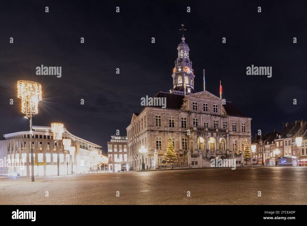 market square with its typical cobblestones in Maastricht illuminated with Christmas lights and with a view on the Statue of Minckeleers and townhall Stock Photo