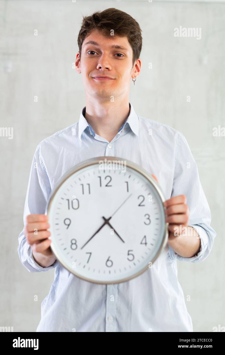 Man with a round big clock in his hands expresses various emotions ...