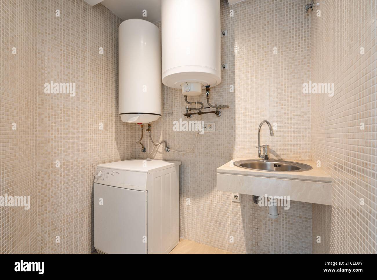 Boilers washing machine and small sink with tap in tiny room Stock