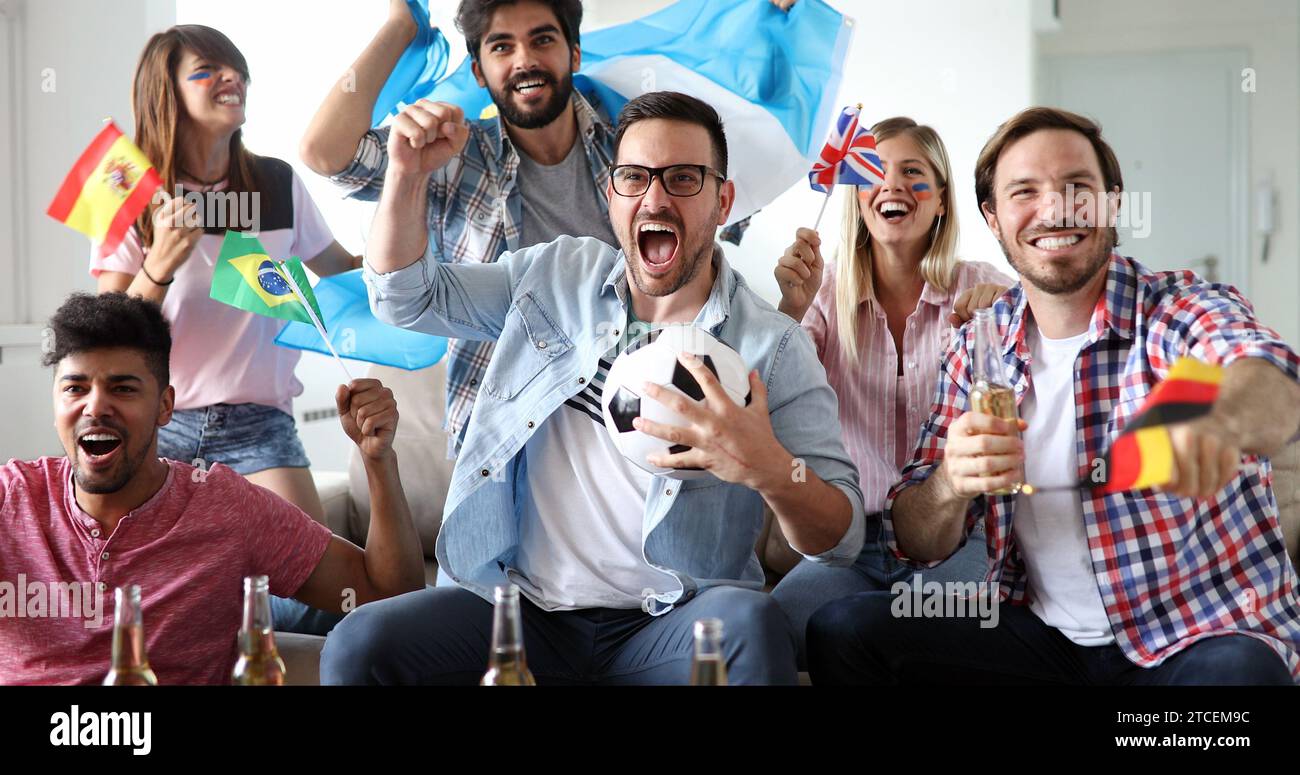 Happy group of young friends watching television and supporting their ...