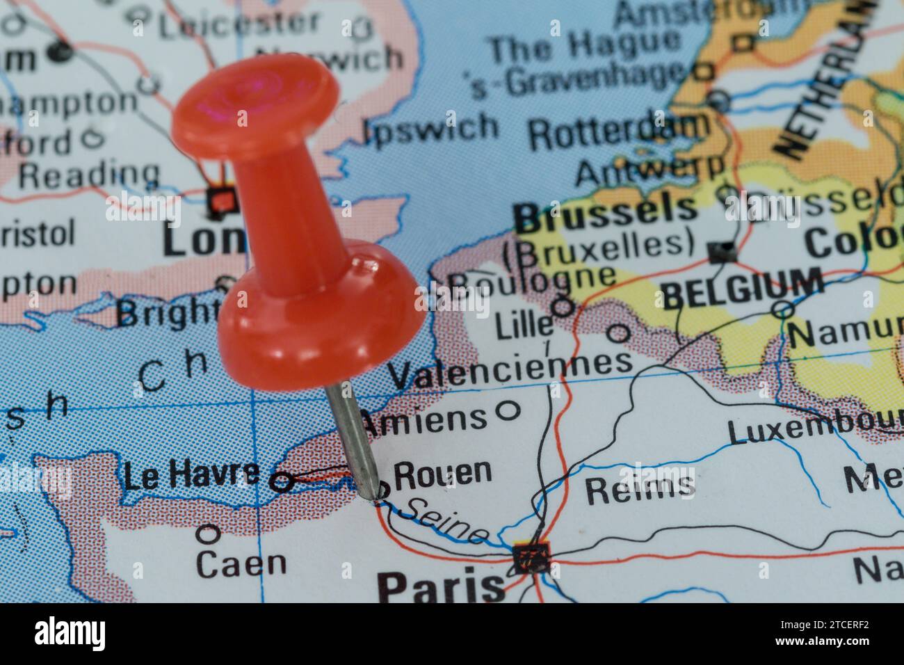 A red pin stuck into a map of Western Europe, pinpointing the location of Rouen Stock Photo
