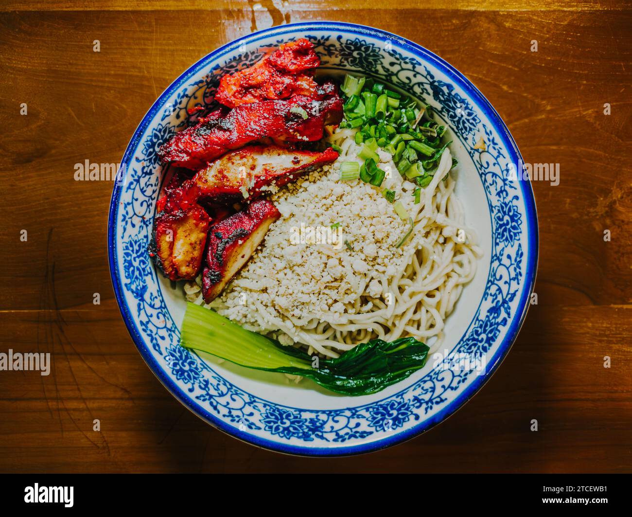 Chinese noodles filled with red pork meat and vegetables on a kopitiam style bowl. Flat lay or top view. Stock Photo